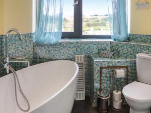 a bathroom with a tub and a toilet and a window at Snowdon Summit View in Llanllyfni +3 photos