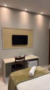 a bedroom with a desk and a tv on a wall at Pousada Capivara Express in Baixas
