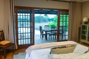 ein Schlafzimmer mit Bett und eine Terrasse mit Tisch in der Unterkunft Hum Lilly in Balgowan