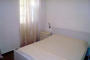 a white bedroom with a bed and a window at Apartments Kuća Grško in Selce