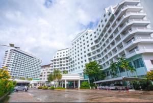 a large white building with cars parked in a parking lot at Royal Palace Hotel in Pattaya Central
