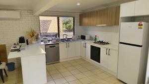 a kitchen with white cabinets and a white refrigerator at Sunnybank Hills Home - Near Shopping & Dining in Brisbane +5 photos