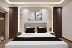 a bedroom with a large white bed with black pillows at Super Hotel O Rudrapur Railway Junction Formerly Krish in Rudrapur