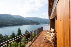 a balcony with two chairs and a view of a river at Casas do Picoto - Gerês Nature and Natural River Beach in Geres