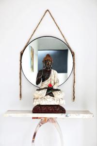 a mirror on a shelf with a statue in front of it at Room Sweet Room, Seminyak in Seminyak