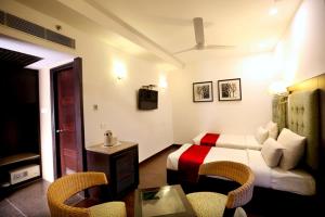 チャンディーガルにあるHotel Oysterのベッド、テーブル、椅子が備わるホテルルームです。