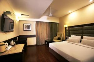 チャンディーガルにあるHotel Oysterのベッドとテレビが備わるホテルルームです。
