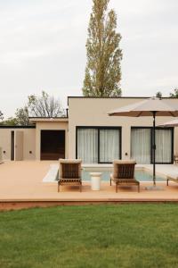 two chairs and an umbrella in front of a house at Like a therapy VILLA in Krčedin