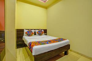 a bedroom with a bed with colorful sheets and pillows at FabHotel Wagholi Inn in Pune