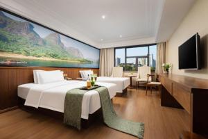 a hotel room with two beds and a large window at Kaibin International Hotel Jingdezhen in Jingdezhen