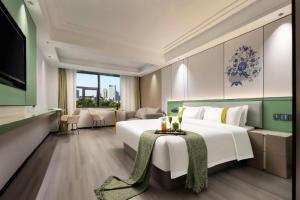 a hotel room with a large bed with a table at Kaibin International Hotel Jingdezhen in Jingdezhen
