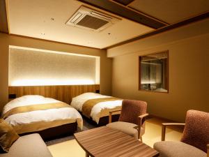 a hotel room with two beds and a table and chairs at Yumekaiyu Awajishima in Sumoto