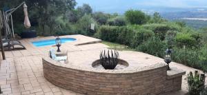 a brick wall around a swimming pool with a fountain at Shamba Yetu Mountain Lodge in Maanhaarrand