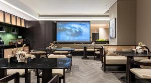 a restaurant with tables and chairs and a large screen at Borrman Hotel Guangzhou Tianhe Sports Center Linhexi Metro Station in Guangzhou
