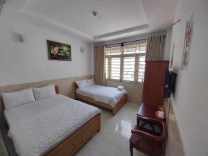 a bedroom with two beds and a television in it at Khách Sạn Thiên Phúc in Ho Chi Minh City