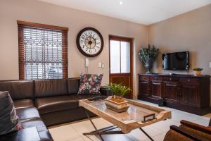 a living room with a couch and a clock on the wall at Avemore Mareba Court No 9 in Stellenbosch