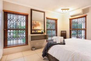 a bedroom with a large white bed and windows at Avemore Mareba Court No 9 in Stellenbosch