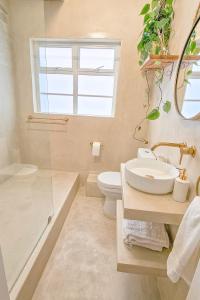 een badkamer met een wastafel en een toilet en een raam bij Bali Beach Flats, Muizenberg in Kaapstad +13 foto's