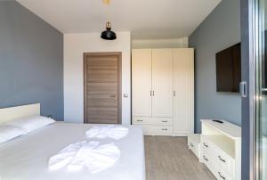 Un dormitorio con una cama blanca y un televisor. en Apartamente Miramare by Alz, en Mamaia Nord – Năvodari