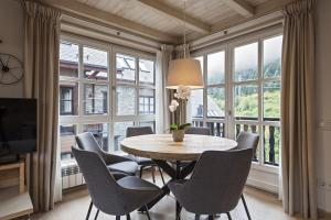 une salle à manger avec une table, des chaises et des fenêtres dans l'établissement Luderna - Apartamento Val de Ruda A30 Manaud, à Baqueira-Beret