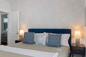 a bedroom with a bed with blue and white pillows at Condo by the Beach King Beds Lush Patio w BBQ Breakers Key One H0MES in Fort Lauderdale