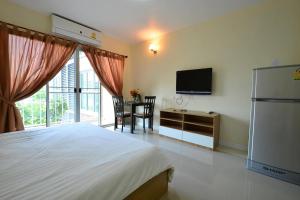 a bedroom with a bed and a tv and a table at The Grow Hotel & Residence in Ban Baen Phichit