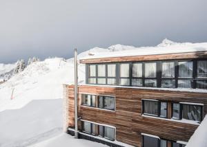 ein Gebäude im Schnee mit schneebedeckten Bergen in der Unterkunft Hotel Manggei Designhotel Obertauern in Obertauern