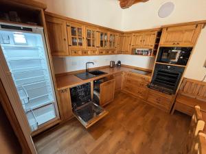 a kitchen with wooden cabinets and an empty refrigerator at Ubytovanie u Čieška in Ábelová