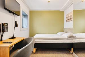 a small room with a bed and a desk and a tv at Klosterhagen Hotel in Bergen