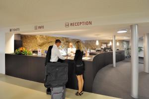 a man and a woman standing at a reception desk at Hotel Pilatus-Kulm in Luzern