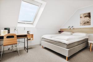 a bedroom with a bed and a desk and a window at Klosterhagen Hotel in Bergen