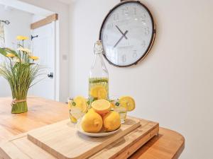 eine Flasche Wein und Orangen auf einem Tisch mit einer Uhr in der Unterkunft Stoney Cottage in Loftus