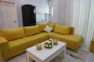 ベラトにあるRaina Luxury Apartmentのリビングルームに置かれた黄色いソファとテーブル