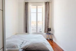 a white bedroom with a bed and a window at Lovely room in Nice in Nice