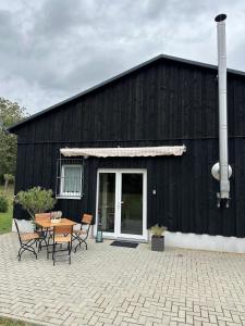 a black barn with a table and chairs in front of it at Ferienhaus LODA - Garten, Netflix & Spreewald Flair in Heinersbrück