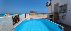 a swimming pool on a balcony with the ocean in the background at Sea sky sleep & repeat in Dawwār ‘Abd Allāh