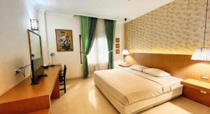 a bedroom with a bed and a desk and a television at HOTEL SARI KURING INDAH in Cilegon