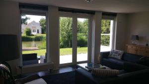 sala de estar con ventanas grandes y sofá en Solo Bungalow, en Makkum