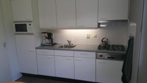 マックムにあるSolo Bungalowの白いキャビネット、シンク、電子レンジ付きのキッチンが備わります。