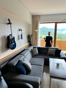 a woman standing in a living room looking out the window at Havasi View Donovaly - 2 Bedrooms, Mountain View, Garage, 2 WC, Balcony, Dishwasher, Guitar, 164 cm TV, Netflix in Donovaly
