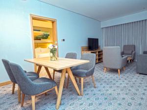 a room with a table and chairs and a television at Casa Diora Hotel Al Rawdah in Jeddah +40 photos