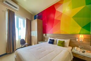 a bedroom with a large bed with a colorful wall at Urbanview Anelia Guest House Syariah Samarinda in Samarinda