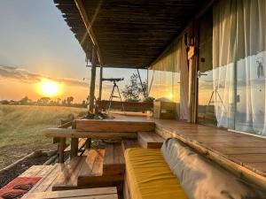 a wooden porch with a view of the sunset at Ole-lekurruki Naromoru Cabins in Naro Moru