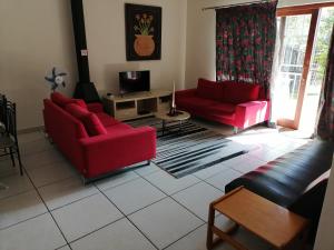 Una sala de estar con dos sofás rojos y un televisor. en BEAL Cultural Village, en Hammanskraal