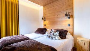 two stuffed animals sitting on a bed in a room at ASAI210-6-2 Appartement 4 étoiles - Les Saisies - 6 personnes in Les Saisies