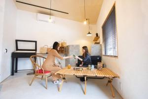 zwei Personen sitzen an einem Tisch in einem Zimmer in der Unterkunft LifeStyleHotel ichi / Vacation STAY 81824 in Kōchi