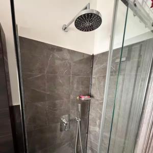 una doccia con una porta in vetro e un soffione di Colle Aurelio Home a Roma