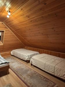 two beds in a room with wooden walls at Pokoje Gościnne u Grażyny in Ojców