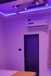 a black door in a room with purple lighting at Maghudiya Homestay in Dwarka