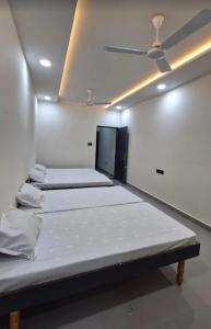 three beds in a room with a ceiling at Maghudiya Homestay in Dwarka